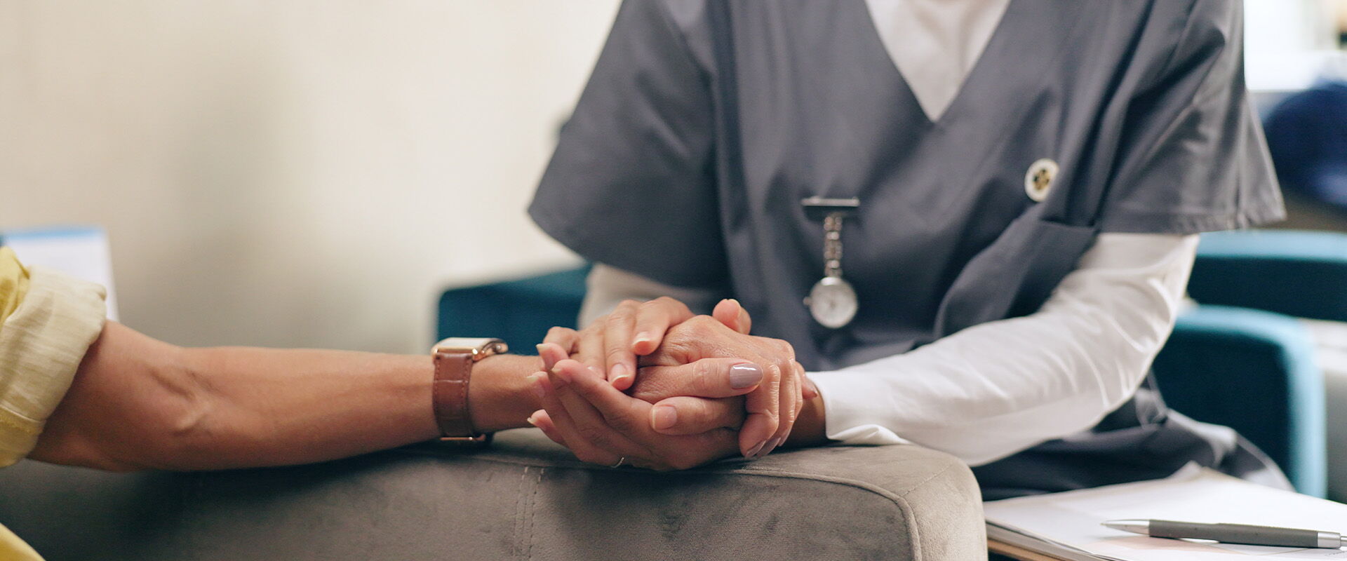 Pflegerin hält einer Seniorin die Hände